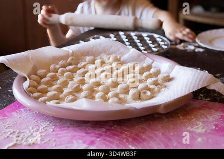 Hausgemachte Teigtaschen auf Teller mit Mehl und Silikonmatte in der Küche Stockfoto