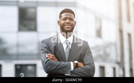Selbstbewusster Geschäftsmann steht tagsüber im Freien in modernem urbanem Ambiente Stockfoto