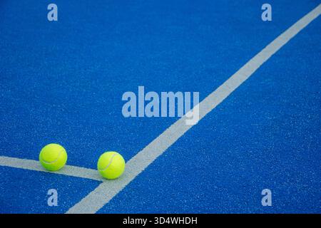 Ein minimalistischer Sporthintergrund, zwei Padel-Bälle auf einem blauen Platz. Stockfoto
