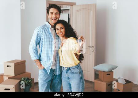 Glückliches Paar, das neues Zuhause mit Keys feiert, nachdem es zusammen eingezogen ist Stockfoto