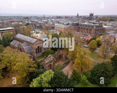 St. John the Baptist Church in Chester, Cheshire, England, umgeben von Herbstbäumen und Stadtgebäuden Stockfoto