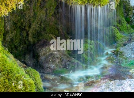 Dreimühlen Wasserfall in Hillesheim, Deutschland. Die lange Exposition erzeugt eine mystische Atmosphäre, in der das Wasser sanft über die Steine fließt. Stockfoto