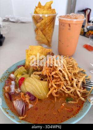 Authentische nordthailändische Khao Soi, eine köstliche Kokosnuss-Curry-Nudelsuppe mit knusprigen Nudeln, eingelegtem Gemüse und roten Zwiebeln. Gepaart mit Referenzen Stockfoto