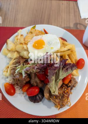 Ein lebendiger, herzhafter Buffetteller mit sonnigem Ei, zartem Fleisch, Pasta, geröstetem Gemüse, frischem Gemüse, und Kirschtomaten, die eine versprechen Stockfoto