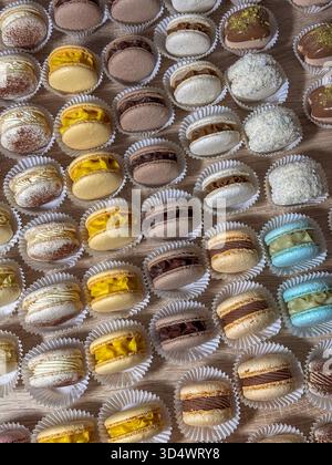 Exquisite, handgefertigte französische Macarons und delikates Mini-Gebäck. Vielfältige Gourmetaromen: Schokolade, Vanille, Zitrone. Akribisch in Papier-cu präsentiert Stockfoto