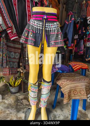 Schaufensterpuppe mit lebendiger traditioneller Kleidung der Hmong-Bergstämme mit aufwändigen Stickereien, Mustern und silbernen Ornamenten in einer belebten lokalen Marke Stockfoto
