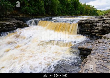 Das sich schnell bewegende Wasser des Flusses Uure wird verschwommen, wenn er über die Aysgarth Falls in Yorkshire fließt. Stockfoto