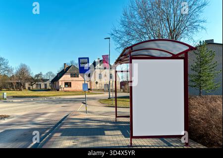 Leere Werbefläche an einer Bushaltestelle, umgeben von Vorstadthäusern an einem klaren Tag Stockfoto