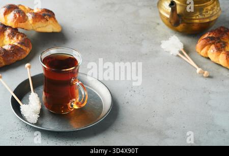 Türkischer schwarzer Tee. Eine Glasschale türkischer schwarzer Tee und knuspriger türkischer traditioneller Bagel auf grauem Betontischhintergrund. Frühstücksgebäck-Konzept. Traditionelles türkisches Heißgetränk. Stockfoto