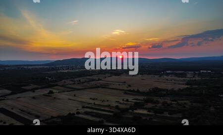 Dramatischer Sonnenuntergang über sanftem Ackerland und Hügeln in der kroatischen oder europäischen Landschaft mit leuchtendem orange-rotem Himmel Stockfoto