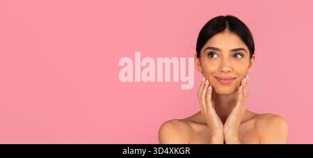 Beautiful young woman touching her face with soft hands and smiling slightly Stockfoto