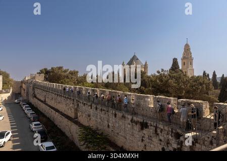 jerusalem, Israel, 2. November 2025, Touristen, die entlang der alten Steinmauern der alten jerusalemer Stadtmauer spazieren, mit der dormitio Abbey und Be Stockfoto
