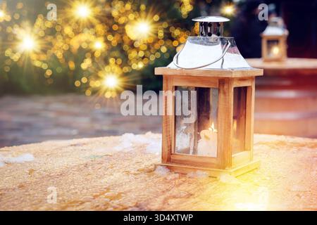 Hölzerne Laterne auf einem Outdoor Cafe Tisch mit Weihnachtsbaum und Lichtern Hintergrund Stockfoto