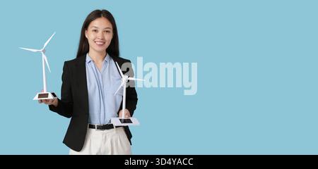 Weibliche asiatische Ingenieurin mit Windturbinenmodellen auf blauem Hintergrund mit Platz für Text Stockfoto
