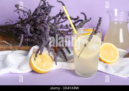Glas kalte Lavendellimonade, Zitronen und Blumen auf farbigem Hintergrund Stockfoto