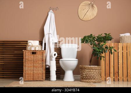 Das Innere des Toiletten mit Toilettenschüssel, Korb und Bademantel Stockfoto
