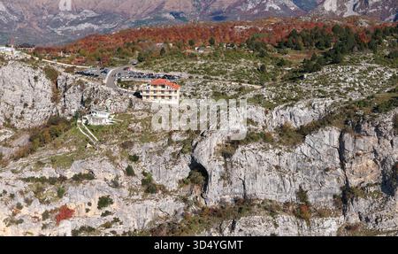 Breites Luftpanorama der Klippen von Sari Salltik und Lodge auf dem Berg Krujë, umgeben von Herbstwald und schroffen albanischen Gipfeln. Stockfoto