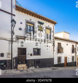 Granada, Spanien - 5. September 2024: Kunstvolles, weißes Gebäude mit bunten Fliesenakzenten und Balkonen an einem sonnigen Tag. Stockfoto