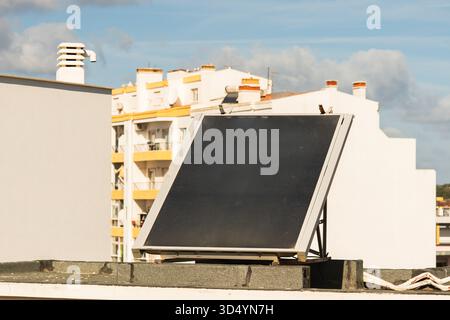 Auf dem Dach eines Wohngebäudes in sonniger städtischer Umgebung ist ein einzelner Solarpanel installiert. Stockfoto