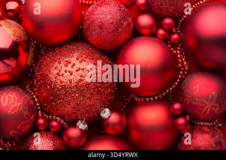 Nahaufnahme von florroten Weihnachtskugeln, verschiedenen Größen, Farben und Texturen. Weihnachten Hintergrund mit roten Kugeln, Ornamenten. Flache Lagen Stockfoto