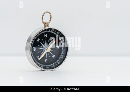 Vintage-Kompass mit schwarzem Zifferblatt isoliert auf weißem Hintergrund. Navigationsgerät mit Pfeilen, die Kardinalpunkte (Norden, Süden, Osten und Westen) anzeigen. Stockfoto