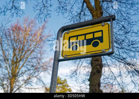 Ein gelbes Verkehrsschild markiert eine Bushaltestelle für die Abholung, das einfache Brett steht an der Straße und zeigt an, wo die Fahrer warten sollten, damit sich der Ort wie ein anfühlt Stockfoto