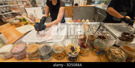Berlin, Deutschland - 19. September 2025: Mitarbeiter der Eisdiele bereitet Dessert mit verschiedenen Toppings zu. Stockfoto