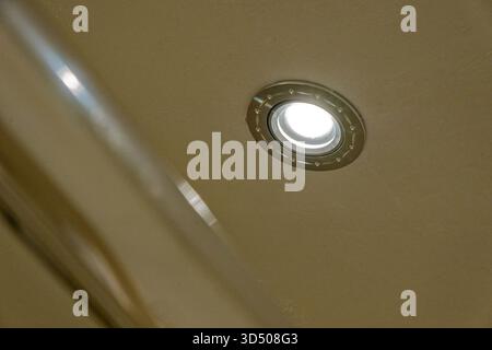 Eine weiße Wand hält ein kleines rundes Metallfenster, das wie ein Bullauge aussieht, die glatte lackierte Oberfläche um das Bullauge bleibt sauber und leer und das silbrige Stockfoto