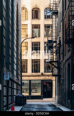 Montreal, Kanada - 11. August 2025: Enge Gasse in der Innenstadt mit Feuerlöchern und Blick auf das klassische Bürogebäude in Montreal Stockfoto