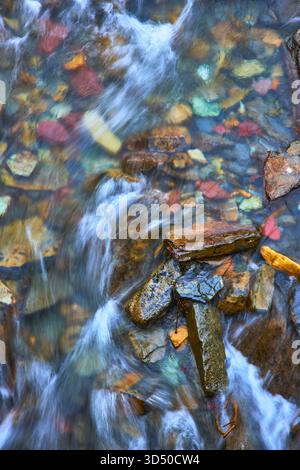 Farbenfrohe Flusssteine und fließende Wasserkaskade in unberührter Natur Stockfoto