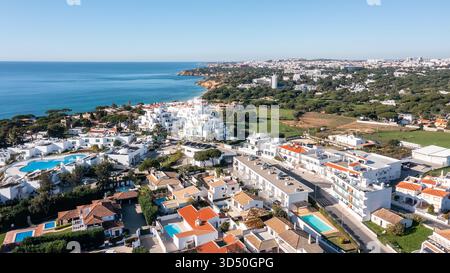 Aus der Vogelperspektive von Olhos de Agua mit weiß getünchten Häusern, Resort-Pools und Küste, die zu Falesia Klippen unter klarem blauem Himmel in Albufeira, Algarve führt Stockfoto