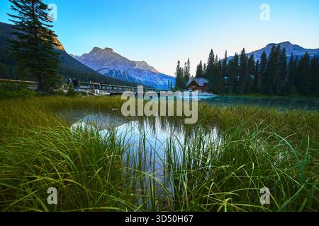 Emerald Lake Hütte und Brücke mit Pine Forest und Berg Reflektionen bei Sonnenaufgang Stockfoto