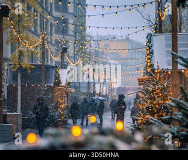 Eine magische Szene auf dem Zürcher Weihnachtsmarkt in der Schweiz, mit funkelnden Lichtern und Schneefall, die ein winterliches Wunderland und defokussiertes Bokeh schaffen Stockfoto