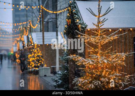 Eine magische Szene auf dem Zürcher Weihnachtsmarkt in der Schweiz, mit funkelnden Lichtern und Schneefall, die ein winterliches Wunderland und defokussiertes Bokeh schaffen Stockfoto