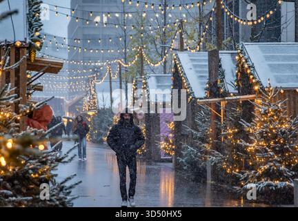 Eine magische Szene auf dem Zürcher Weihnachtsmarkt in der Schweiz, mit funkelnden Lichtern und Schneefall, die ein winterliches Wunderland und defokussiertes Bokeh schaffen Stockfoto