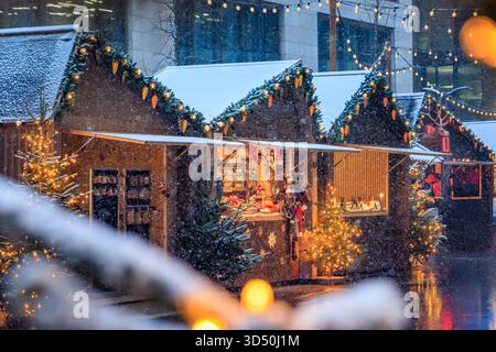 Eine magische Szene auf dem Zürcher Weihnachtsmarkt in der Schweiz, mit funkelnden Lichtern und Schneefall, die ein winterliches Wunderland und defokussiertes Bokeh schaffen Stockfoto