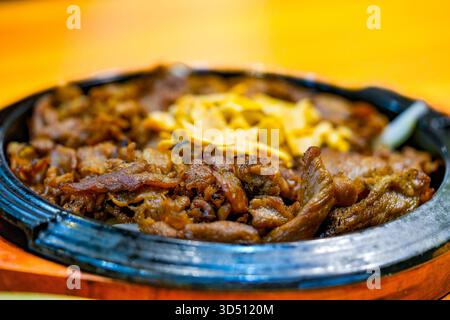 Bulgogi wird auf einer heißen Platte serviert und mit trockenem Knoblauch bestreut. Koreanisches Essen. Stockfoto