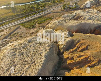 Ein Blick aus der Vogelperspektive zeigt eine mehrspurige Autobahn, die neben massiven, dramatisch erodierten gelben und roten Felsformationen und einer tiefen, engen Schlucht verläuft Stockfoto