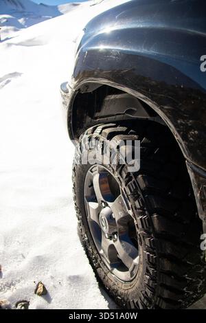Naryn, Kirgisistan - 12. November 2025: Nahaufnahme des robusten Reifens und Rades eines schwarzen Toyota Land Cruiser 4x4, der bei hellem Sonnenlicht auf einem fährt Stockfoto