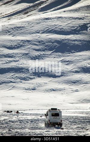 Naryn, Kirgisistan - 12. November 2025: Die Rückansicht eines weißen UAZ Patriot 4x4, der durch eine verschneite Ebene fährt, mit sichtbaren Spuren, die den V hinaufführen Stockfoto