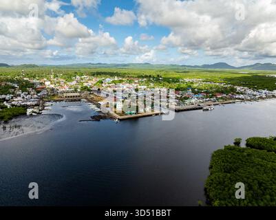 Farbenfrohe Küstenstadt mit Häusern, Hafen und Fischerbooten, umgeben von tropischem Grün und fernen Hügeln. Siargao, Philippinen. Stockfoto