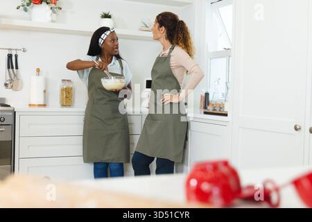 Rührteig und plaudern, verschiedene Freundinnen kochen in einer hellen Küche, mit Schneebesen Stockfoto