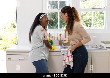 Diverse Friends Reinigungsbecken in der Küche, mit gelben Handschuhen und Geschirrständer Stockfoto