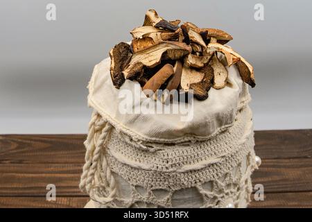 Getrocknete Bio-Stachelpilze in handgefertigter Tasche auf rustikalem Holztisch Stockfoto