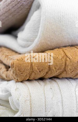 Nahaufnahme warmer Strickpullover in Pastellfarben und Beige, ordentlich gestapelt. Stockfoto