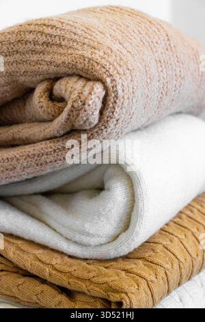 Nahaufnahme warmer Strickpullover in Pastellfarben und Beige, ordentlich gestapelt. Stockfoto