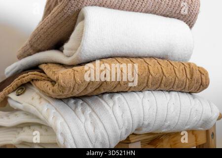 Nahaufnahme warmer Strickpullover in Pastellfarben und Beige, ordentlich gestapelt. Stockfoto