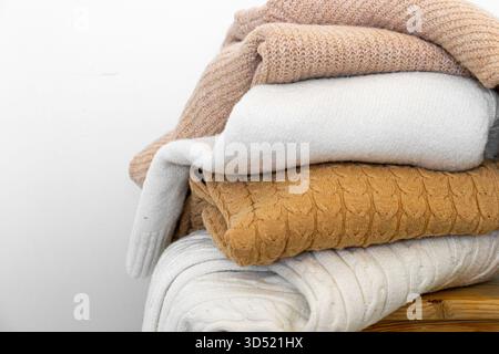 Nahaufnahme warmer Strickpullover in Pastellfarben und Beige, ordentlich gestapelt. Stockfoto