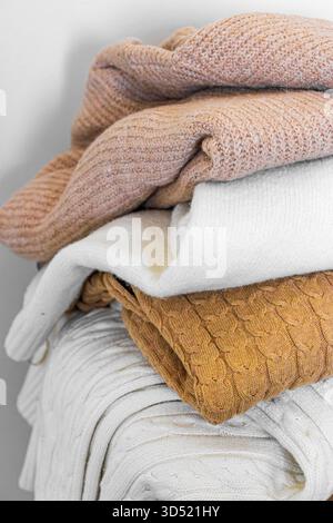 Nahaufnahme warmer Strickpullover in Pastellfarben und Beige, ordentlich gestapelt. Stockfoto