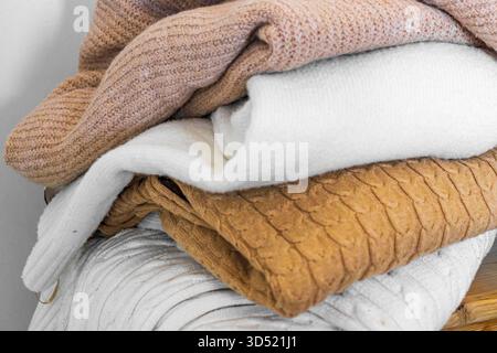Nahaufnahme warmer Strickpullover in Pastellfarben und Beige, ordentlich gestapelt. Stockfoto